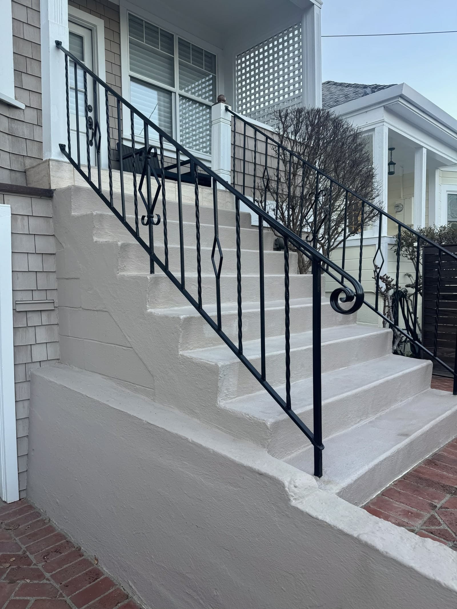 Exterior stair railing with black metal handrails.