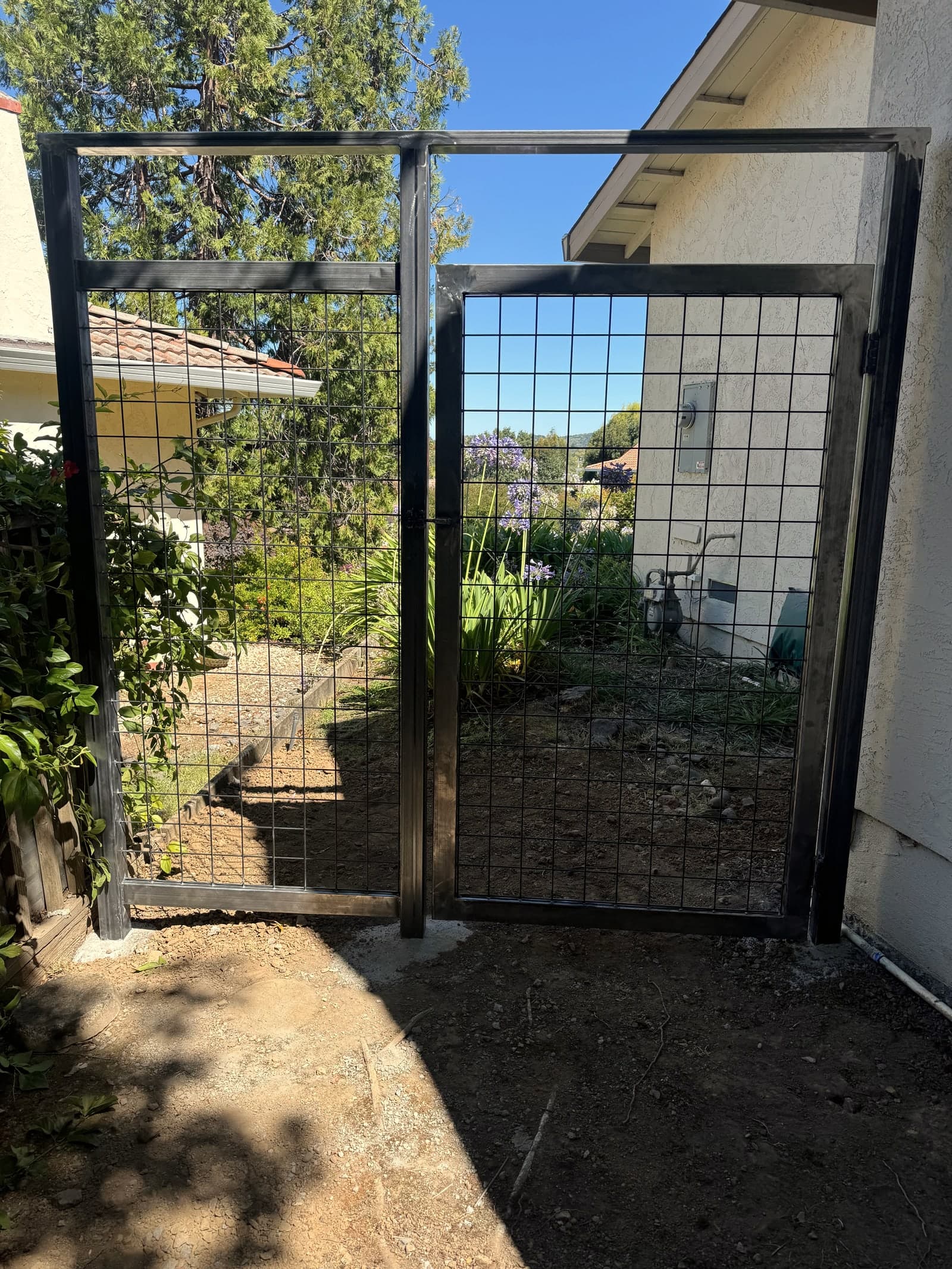 Black metal mesh garden gate with square-grid panels.